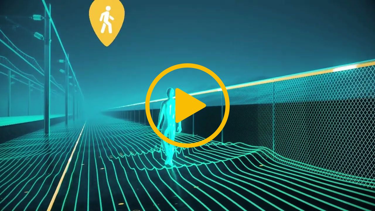 A video thumbnail with a play icon in the centre - The CGI video highlights railway security. A person is walking down the railway. Near them is a yellow fiber optic cable. A warning pin is appearing from the top of the screen indicating a person walking showing that the person has been detected by distributed acoustic sensing.