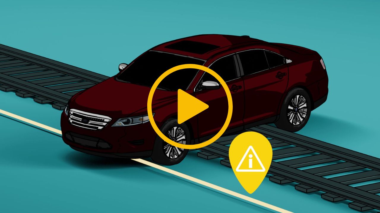 A video thumbnail with a play icon in the centre. There is a car stuck on top of a railway track. A warning icon is present above a fiber optic cable running alongside the track to represent vehicle intrusion detection by Distributed Acoustic Sensing.