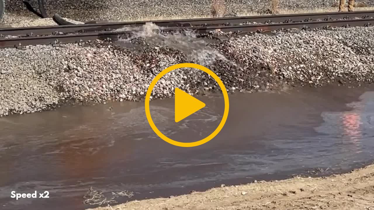 A video thumbnail with a play icon in the centre - The video shows a railway track being washed away be flowing water known as a washout. 